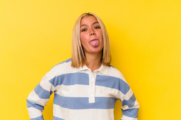 Poster - Young venezuelan woman isolated on yellow background funny and friendly sticking out tongue.