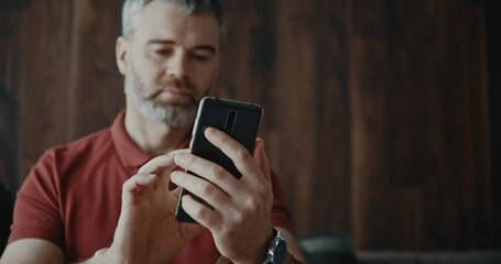 Wall Mural - Caucasian bearded adult millennial with mobile phone typing messages to busiess partner communicating social media application sharing news online.