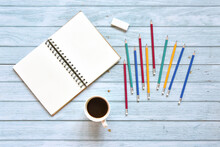 Still Life, Business Office Supplies Education Concept, Top View Image Of Open Notebook With Coffee And Various Colorful Pencil With Blank Pages On Blue Sky Wooden Background, Ready For Adding Text