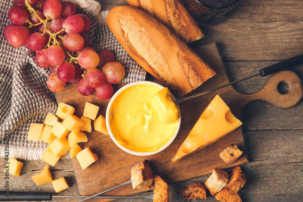 Cheese fondue and different snacks on wooden background
