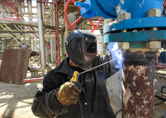 professional welder cooks the horizontal joint of the pipeline of the enterprise plant dn150 under the gate valve