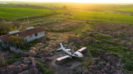 Abandoned broken plane in a field in countryside during sunset, aerial view