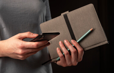 Poster - Female hands holding phone and making appointments, holding planner. Student using smartphone and notebook at night