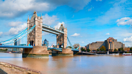 Wall Mural - Tower Bridge on a bright sunny day with blue sky and clouds. Calm water with reflections. London, England, UK.