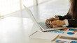 © ArLawKa - A business woman working in an office sitting at a business statistical chart analysis desk holding a chart using a laptop