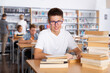© JackF - Schoolboy sitting with stacks of books in school library indoor