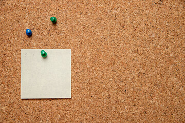 Canvas Print - Closeup shot of three pins and an empty white paper with space for text on a corkboard