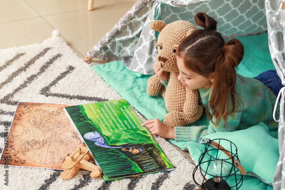 Cute little girl reading book at home