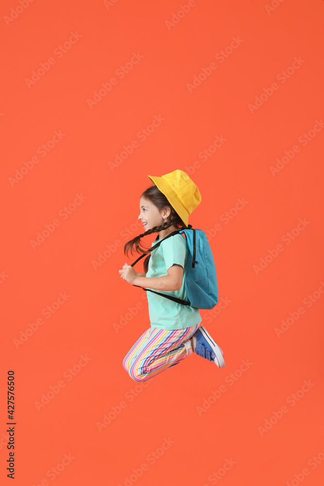Jumping little girl with backpack on color background