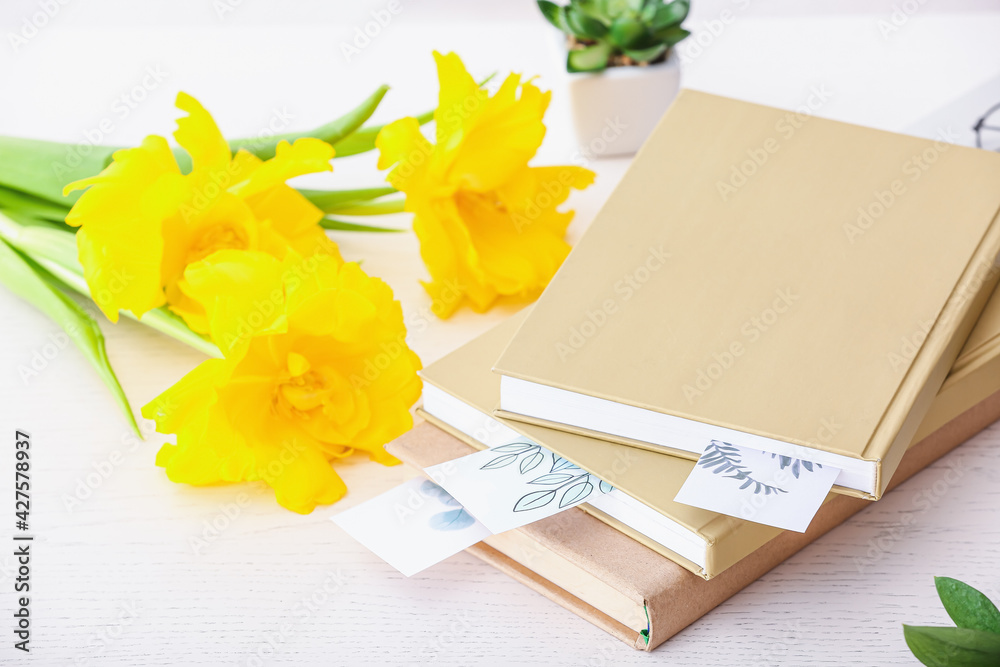 Books and flowers on light background