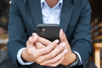 young Businessman in suit holding and using smartphone for sms messages, man typing touchscreen mobile phone in office or cafe. business, lifestyle, technology and Social media network concept