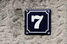 7 Seven House Number Plate Hanged On A Concrete Fence. Arhitectural Detail.