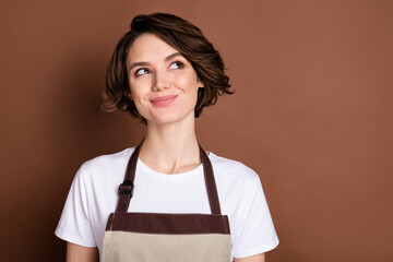 Sticker - Photo of young smiling charming lovely woman barista look copyspace dreaming isolated on brown color background