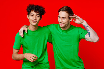 Two man green t-shirts embrace emotions friendship red background