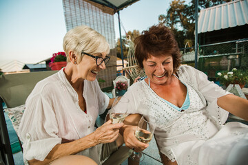 Wall Mural - Senior female friends enjoying a day in the cottage near the river, having fun.