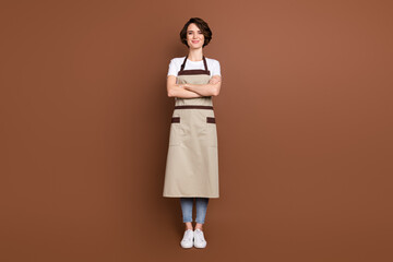 Poster - Full length body size view of lovely content cheery girl barista coffee shop seller folded arms isolated over brown color background