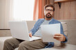 © Seleznov_Molchanova - Entrepreneur works with a laptop and keeps a document in a home office