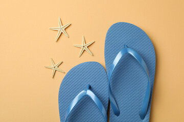 Blue flip flops and starfishes on beige background