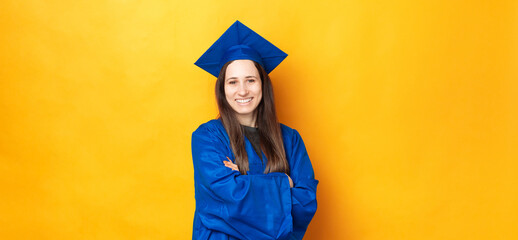 Portrait of smiling young cheerful woman graduating and wearing blue robe