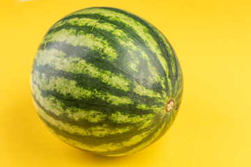 Wall Mural - Green watermelon on yellow background side view