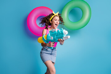 Sticker - Photo of young excited girl happy positive smile go run play game water gun swim ring isolated over blue color background