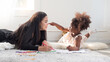 © Dollydoll - Cute little mixed race toddler girl pointing on Asian mother nose while doing coloring or homeschooling. Mother daughter bonding time.