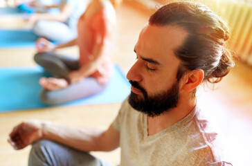 Canvas Print - fitness, yoga and healthy lifestyle concept - man with group of people meditating in lotus pose at studio