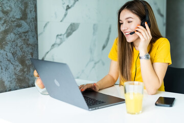 Freelance operator woman talking with headsets and consulting clients from home office.