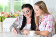 © aletia2011 - Smiling mother and daughter sitting at table and using digital tablet