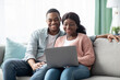© Prostock-studio - Happy african american family sitting on couch, using laptop