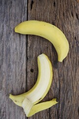 Wall Mural - Half peeled banana tropical fruit on wood background or texture