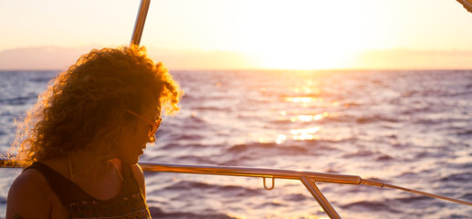 Wall Mural - Portrait of attractive middle age woman sitting on the wooden deck of the yacth enjoying the trip -  concept of luxury lifestyle with yacht - female people summer day tourist