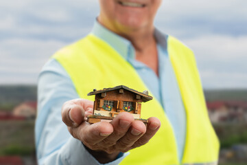 Wall Mural - Selective focus close-up miniature wooden house held by builder