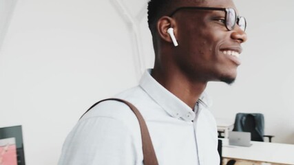 Wall Mural - A pleased african businessman wearing eyeglasses is walking in the office