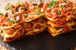 Italian Vincisgrassi or vincesgrassi, is a typical Marche pasta dish similar to lasagne al forno closeup in the slate board on the table. horizontal