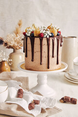 Poster - Vertical shot of a delicious chocolate and berry cake on a stand with candies around it