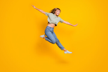 Poster - Full length body size view of lovely cheerful girl jumping having fun flying like aircraft isolated over bright yellow color background