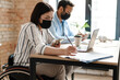 © Drobot Dean - Multiracial two colleagues in face mask using smartphone while working