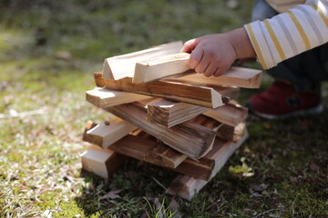 boy working on a stack of firewood kindling at a garden. boy plays with woods at the park in the spring