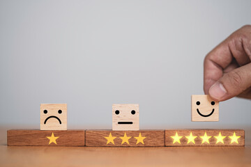 Poster - Hand putting smiley face and golden yellow stars which print screen on wooden cube block for customer survey quality of product and service , Customer evaluation scorecard concept.