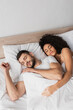 © LIGHTFIELD STUDIOS - high angle view of multiethnic couple sleeping in bed