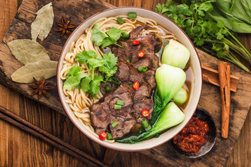 Spicy red soup beef noodle in a bowl on wooden table