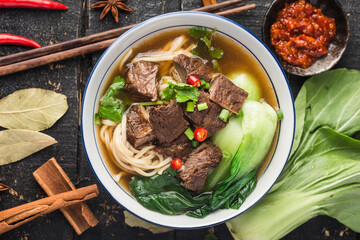 Wall Mural - Spicy red soup beef noodle in a bowl on wooden table