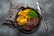 Grilled Meat Beef Steak With Potato Chips French Fries And Green Peas Salad On Rustic Metal Plate On Stone Background Table From Above 