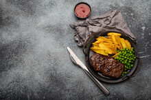Grilled Meat Beef Steak With Potato Chips French Fries And Green Peas Served With Red Tomato Sauce On Rustic Metal Plate On Stone Background Table From Above With Space For Text