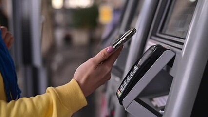 Close-up of a woman paying at a self-service machine using a contactless phone payment