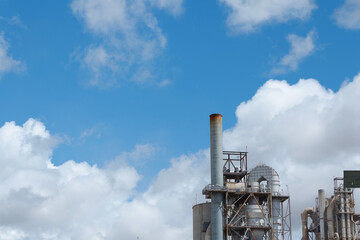 metallic pipes against vivid blue sky with clouds. industrial background. concepts of global warming