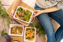 girl hands are holding plastic container salad with rucola beetroot and feta cheese. food delivery concept. unrecognizable people