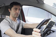 © Josu Ozkaritz - Young man taking cellphone from mobile holder while driving. Male driver using smart phone in car
