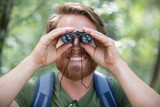 Fototapeta Młodzieżowe - close-up of male hiker looking through binoculars in forest